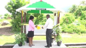 (l-r) Neva Manners-Limonta, Deputy Comptroller at the Inland Revenue Department and Collin Dore, Permanent Secretary in the Ministry of Finance commissioning the state-of-the-art bus stand on the Island Main Road near Horsford’s Valu Mart adopted by the department on Nevis on August 12, 2016